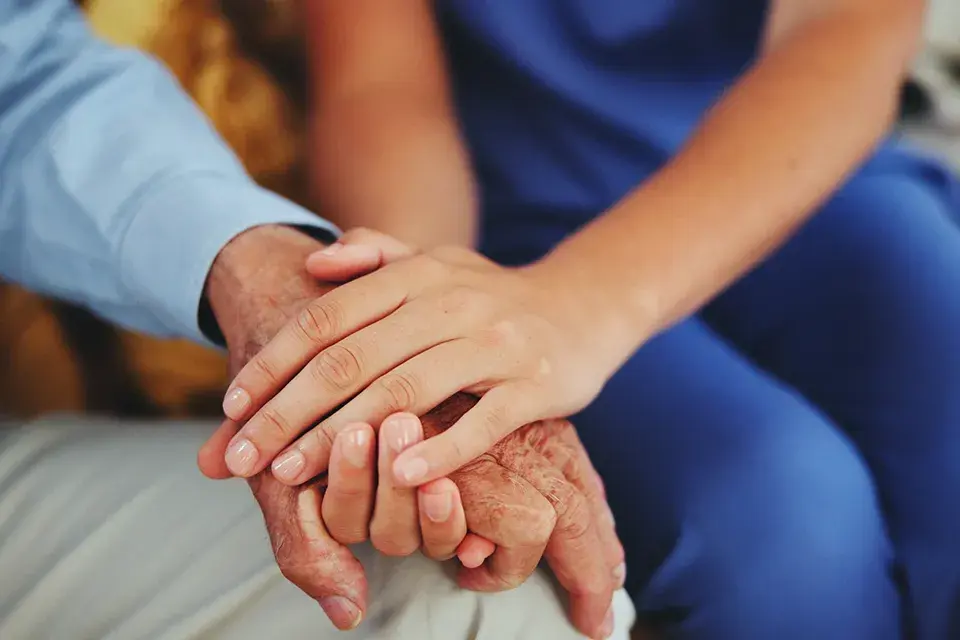 Close-up of a doctor's hand gently holding a patient's hand, symbolizing the compassionate and personalised care at DS Eye Surgeon in Birmingham, as reflected in Doreen's heartfelt testimonial